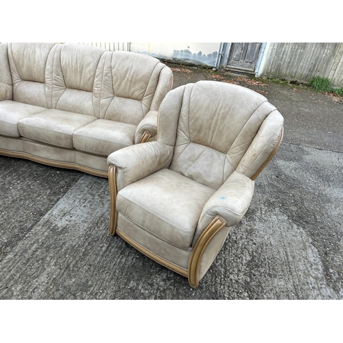 215 - A golden brown leather three piece lounge suite consising of sofa and two armchairs.