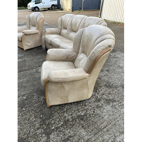 215 - A golden brown leather three piece lounge suite consising of sofa and two armchairs.