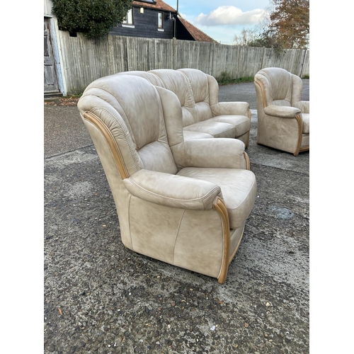 215 - A golden brown leather three piece lounge suite consising of sofa and two armchairs.