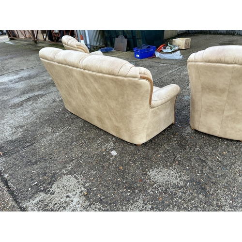 215 - A golden brown leather three piece lounge suite consising of sofa and two armchairs.