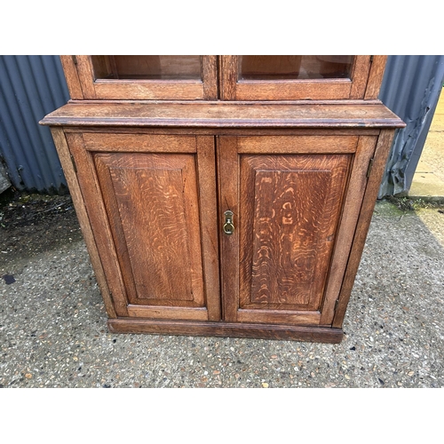 227 - An early 20th century oak glazed bookcase cupboard 96x47x198