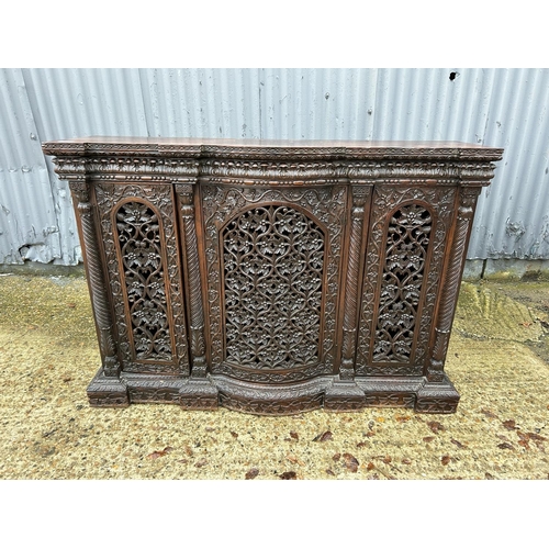 243 - An antique Burmese hardwood side cabinet, ornately carved 132x38x97 cms