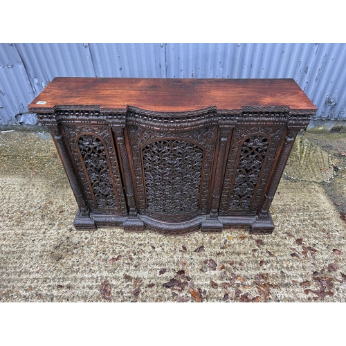 243 - An antique Burmese hardwood side cabinet, ornately carved 132x38x97 cms