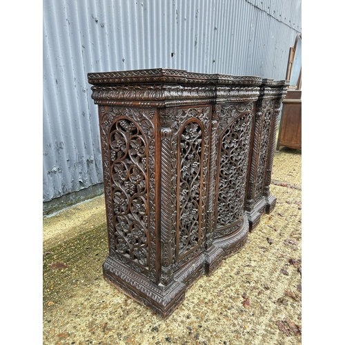 243 - An antique Burmese hardwood side cabinet, ornately carved 132x38x97 cms