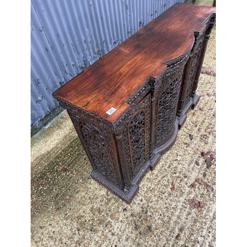 243 - An antique Burmese hardwood side cabinet, ornately carved 132x38x97 cms