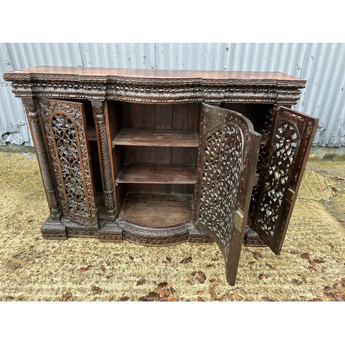 243 - An antique Burmese hardwood side cabinet, ornately carved 132x38x97 cms