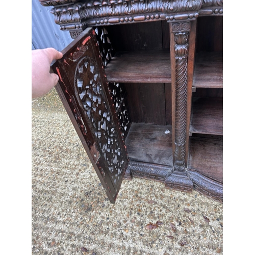 243 - An antique Burmese hardwood side cabinet, ornately carved 132x38x97 cms