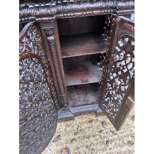 243 - An antique Burmese hardwood side cabinet, ornately carved 132x38x97 cms