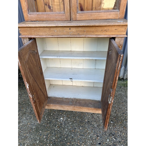 41 - A continental pine bookcase cupboard with a glazed top over two door cupboard base 100x45x227