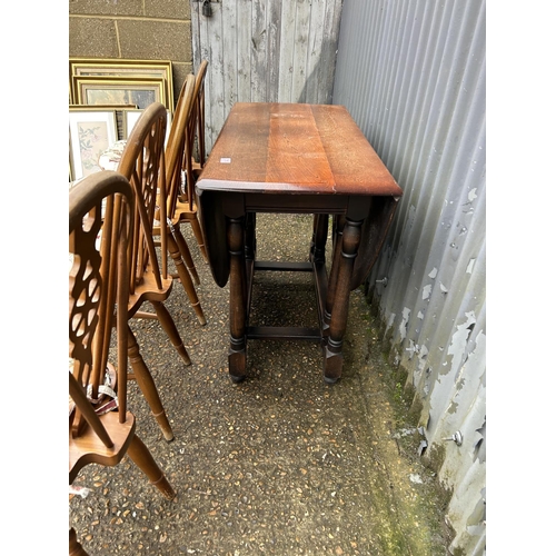 210 - An oak gateleg table together with four wheelback dining chairs