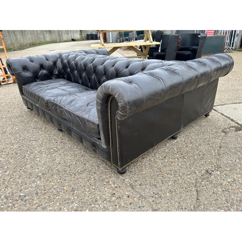 174 - An unusual thick black leather back to back chesterfield sofa with brass studwork 170x240