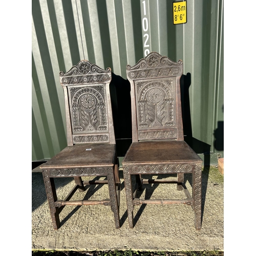 250 - A pair of antique oak chairs with carved panel backs