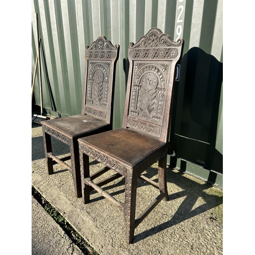 250 - A pair of antique oak chairs with carved panel backs