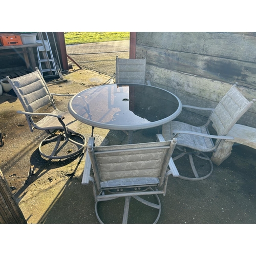 369 - A circular glass top garden table with four swivel chairs