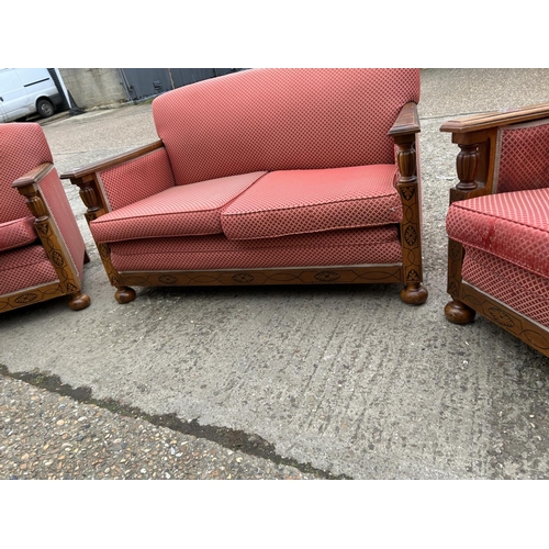 23 - An early 20th century oak framed three piece lounge suite consisting of two seater sofa with two cha... 