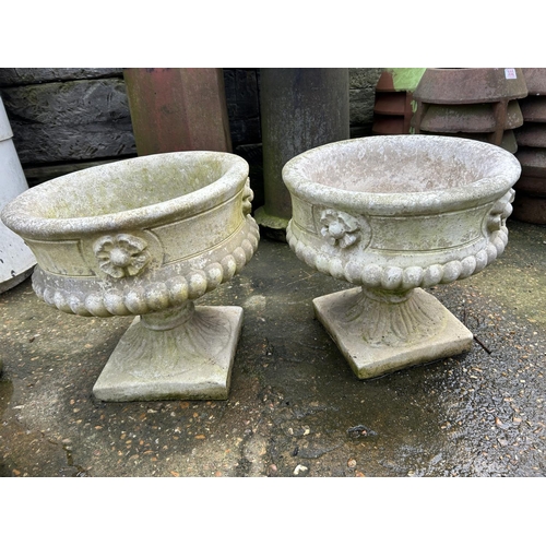 334 - A pair of concrete garden urns on plinths