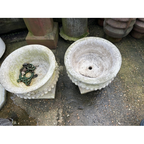 334 - A pair of concrete garden urns on plinths