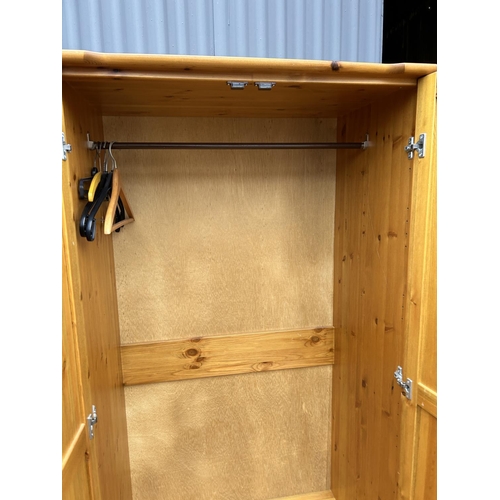 88 - A pine double wardrobe together with matching three drawer bedside