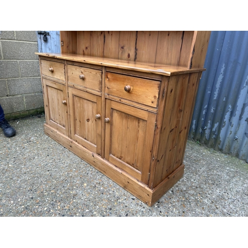 157 - A solid pine dresser with leaded glass plate rack back over three drawer base 156 cm wide