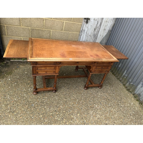 37 - A  large continental mahogany writing desk, five drawers and two sliding extensions with a golden le... 