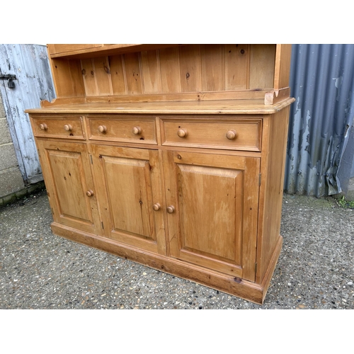 73 - A large solid pine dresser with cabinet top over three drawer base 152x50x20