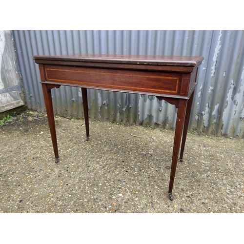 43 - An Edwardian mahogany inlaid fold over card table with cards