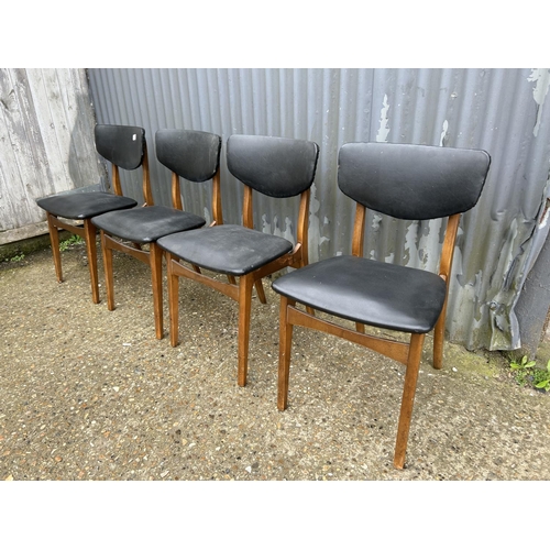 80 - A set of four teak dining chairs with black vinyl seats