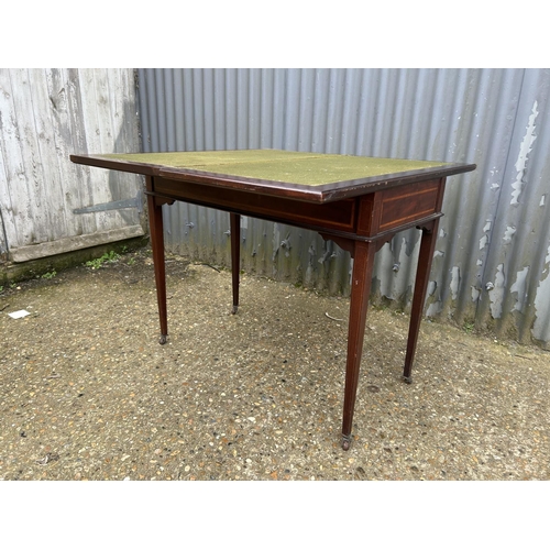 101B - An Edwardian mahogany inlaid fold over card table with cards