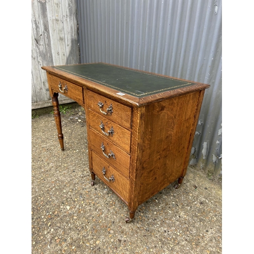 166 - An oak kneehole writing desk with a green leather top 108x56x75