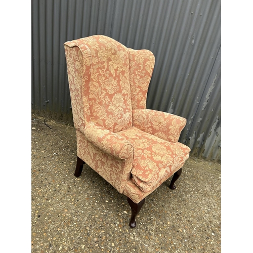 18 - A terracotta upholstered wing back chair