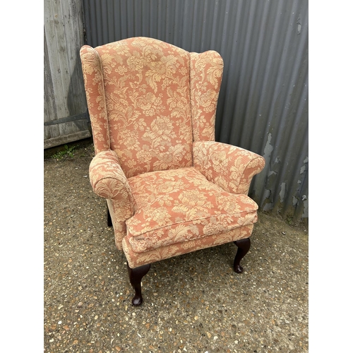 18 - A terracotta upholstered wing back chair