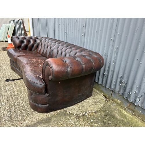 157 - A brown leather kidney shaped chesterfield sofa