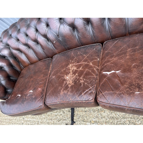 157 - A brown leather kidney shaped chesterfield sofa