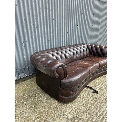 157 - A brown leather kidney shaped chesterfield sofa