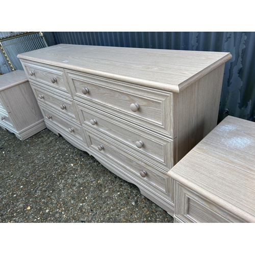 182 - A modern light oak effect lowboy chest of six drawers together with a pair of matching bedsides larg... 