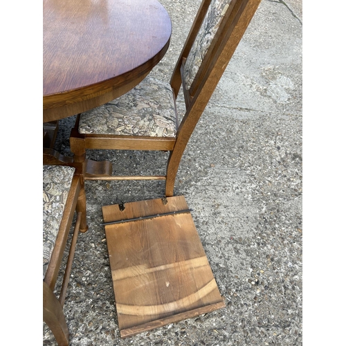 194 - A circular oak dining table with four chairs and extension leaf