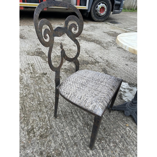 176 - A circular iron framed bistro table with marble top and two iron framed chairs