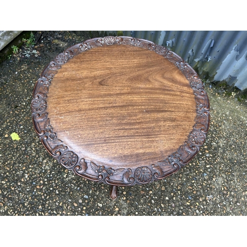 212 - An ornate carved mahogany occasional  table 66 diameter x 50 high