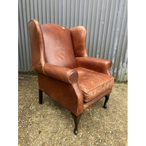 235 - A tan brown leather wing back armchair