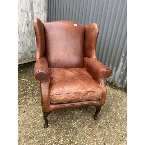 235 - A tan brown leather wing back armchair