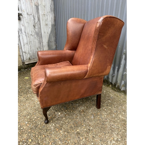 235 - A tan brown leather wing back armchair