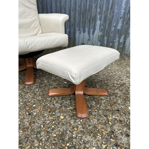 63 - A modern cream leather easy chair with matching stool