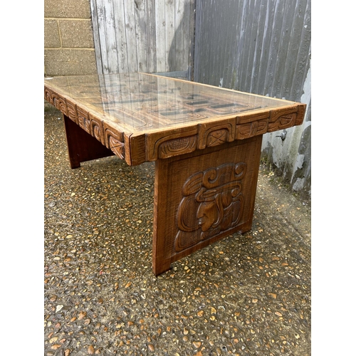 86 - A carved hardwood ethnic style coffee table with drop in glass top 107x56x47