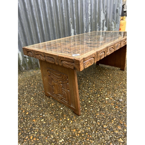 86 - A carved hardwood ethnic style coffee table with drop in glass top 107x56x47