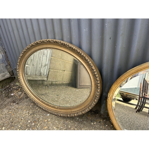 105 - Two large oval gold gilt mirrors together with two smaller wall mirrors