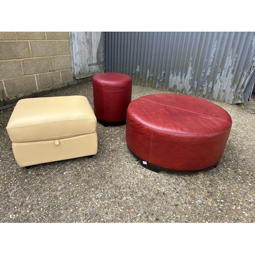 130 - A large red leather footstool 88cm round together with another red stool and a cream storage footsto... 