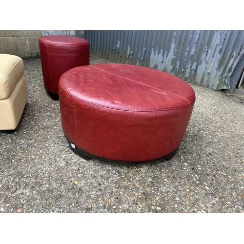 130 - A large red leather footstool 88cm round together with another red stool and a cream storage footsto... 