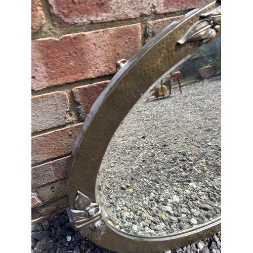 364 - A arts and crafts style planished brass oval wall mirror decorated with roses  85x60