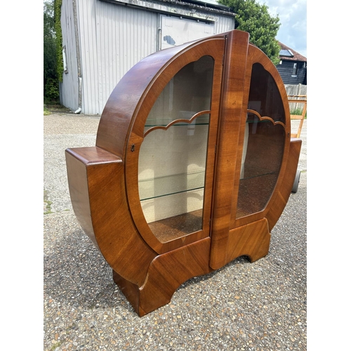 62 - An art deco walnut Wheel cabinet with glazed doors and two glazed shelves 137cm wide