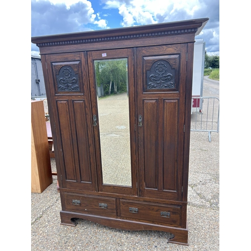 66 - A large carved oak three door wardrobe on two drawer base 155x50x205